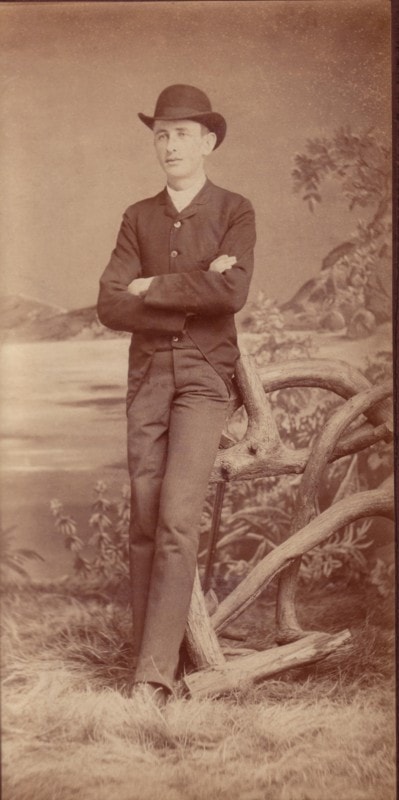 Carl Ahrens standing with arms crossed in a studio portrait, circa 1880, wearing a bowler hat