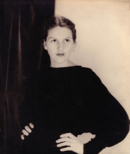 Chloris Ahrens standing against a dark curtain in a studio portrait, 1930