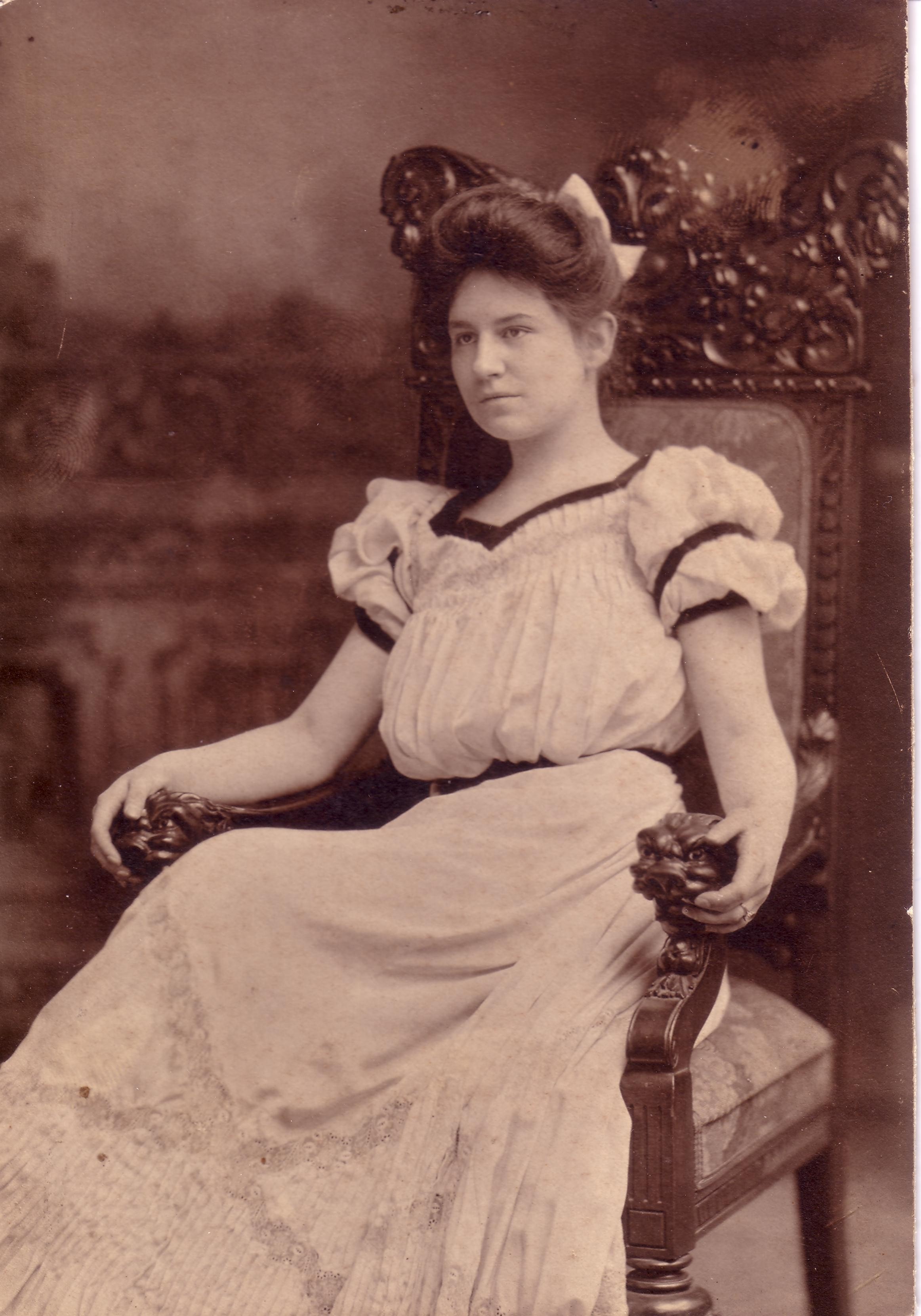 Martha Madonna Ahrens seated in an ornate chair in a formal studio portrait, circa 1909, wearing a white dress