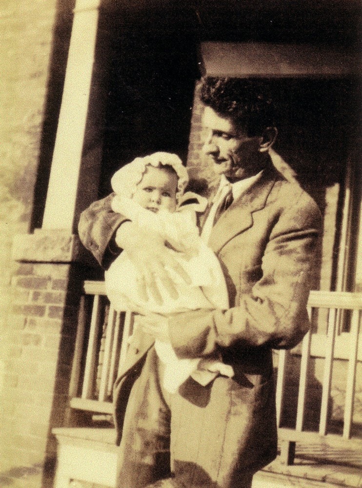 Carl Ahrens holding baby Sigrid on a porch