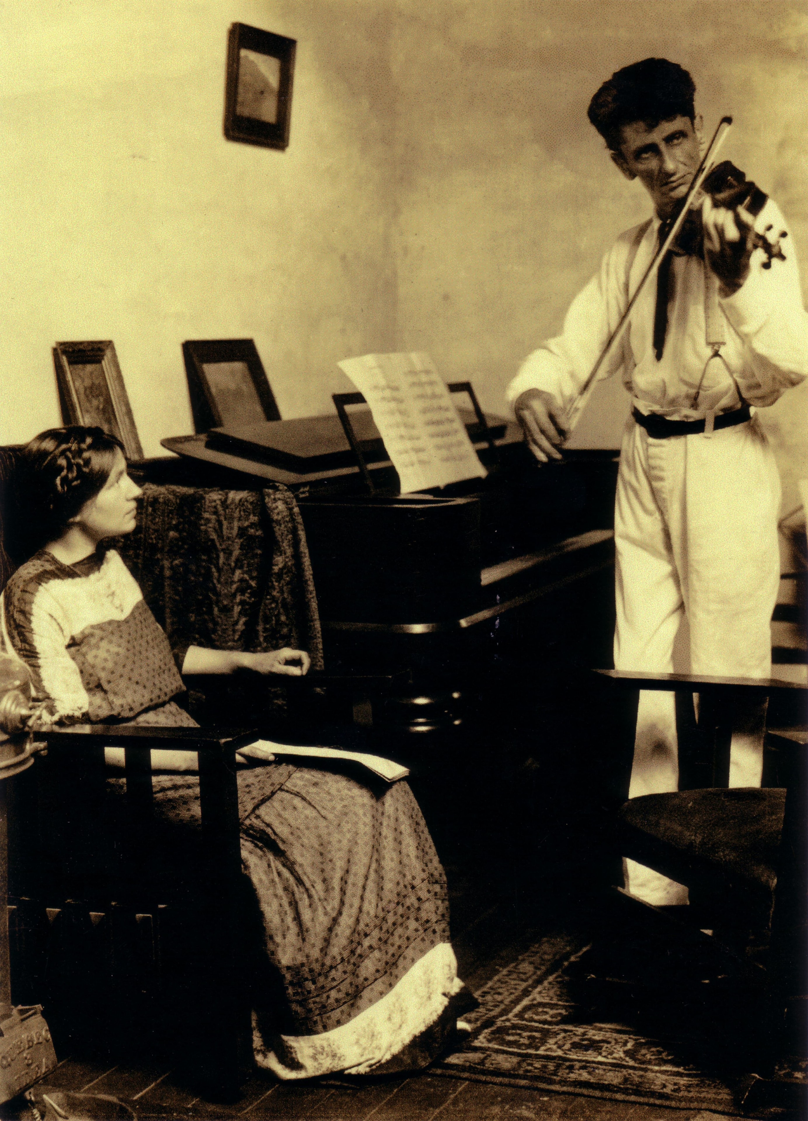 A violinist performing beside a pianist at a piano